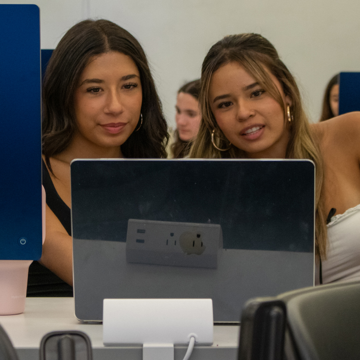 Two students looking at a laptop screen